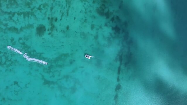 A couple rides on a jet ski, drawing a whimsical pattern in the water. Aerial view