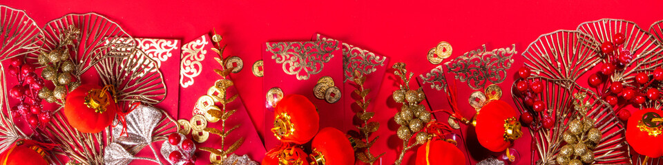 Chinese New Year gold red background. Lunar New Year greeting card flatlay with traditional festival decoration - ginkgo biloba branches decor, twigs, berries, gift envelopes, coins, Chinese lanterns