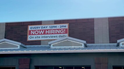 4k pan of sign that states Now Hiring outside of storefront