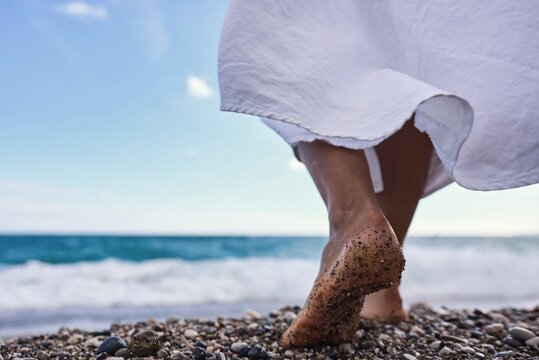 Women's feet in the sea. Close-up side view of a young woman's bare feet on a sandy sea beach at sunset. High quality photo