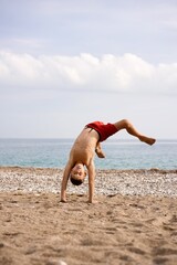 kid does acrobatics on the beach. High quality photo