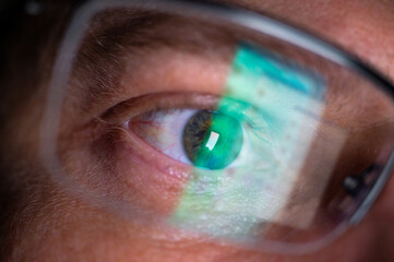 Männliches Auge mit Brille und Spiegelung des Displays eines Smartphones