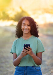 Beautiful smiling girl with curly hairstyle using smart phone