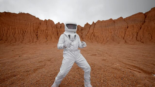 An astronaut dances on the surface of the red planet. Stylish movements of modern dance due to the conquest and colonization of new worlds