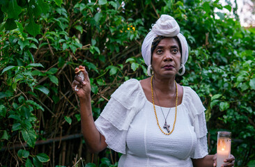 Woman in garden praying with candle and rosary