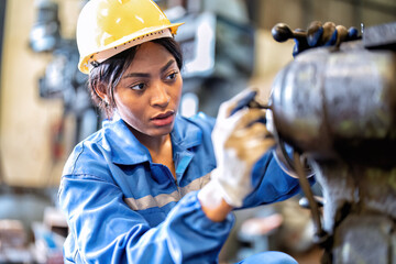 Woman in uniform working in machinery shop trouble shooting repair faulty mechanical rotating part