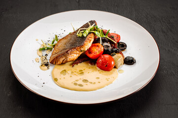 Tasty grilled dorada fish with boiled vegetables and sauce on wooden background