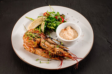 Dish of big king shrimps with herbs on wooden background