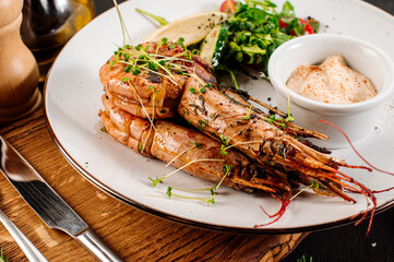 Dish of big king shrimps with herbs on wooden background