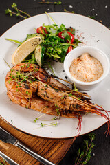 Dish of big king shrimps with herbs on wooden background
