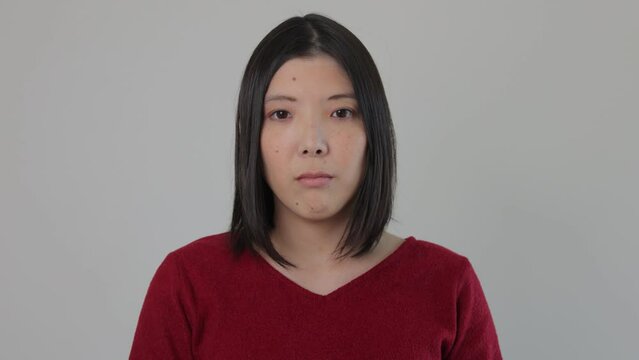 Young Japanese woman opens her eyes and stares the camera. Emotionless, Still, Protest.