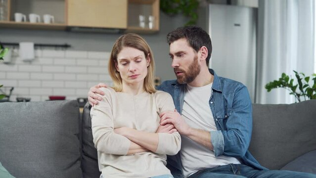 Guilty bearded husband trying to apologize to offended worried young woman after family conflict Young man calms and supports wife with serious problems at work or personal mental health crisis