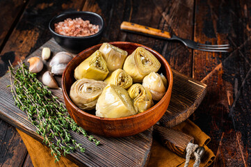 Appetizer Artichoke hearts pickled in olive oil with herbs and spices Wooden background. Top view