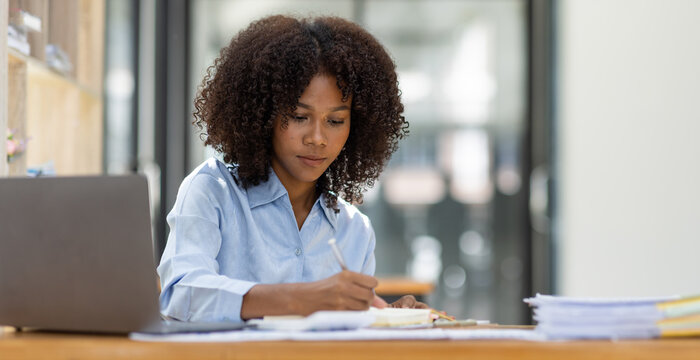 Successful african american accountant business woman work documents tax on laptop computer in office. finance investment economy and marketing research concept.