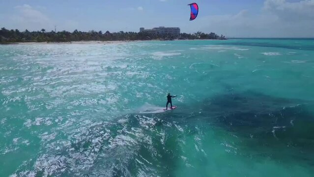 Kitesurfing in turquoise water of tropical beach paradise in warm waters at bright sunny day. Aerial view