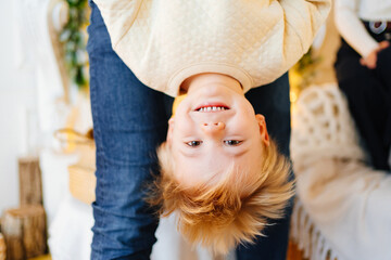 dad plays with his son and holds him upside down. father-child games. 