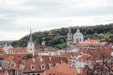 Fototapeta premium Prague cityscape with view of Nicholas Cathedral and orange building roofs in autumn