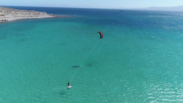 Kitesurfing in turquoise water of tropical beach paradise in warm waters at bright sunny day. Aerial view
