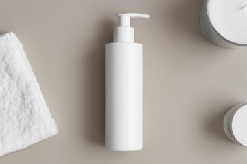 Obraz na płótnie Canvas White cosmetic shampoo dispenser bottle mockup with a towel on the beige table.
