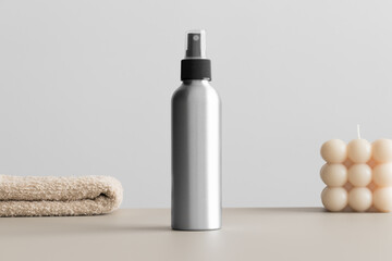 Aluminium cosmetic spray bottle mockup with a candle and a towel on the beige table. - obrazy, fototapety, plakaty