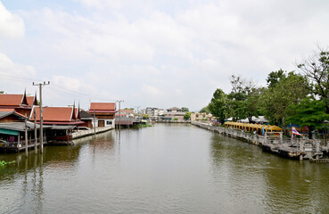 Fototapeta na wymiar BANGKOK, THAILAND - NOVEMBER 20, 2022 : Wooden houses, Thai houses and buildings along the Chao Phraya River with white clouds and blue sky background, Town Ayutthaya Waterfront, Thailand.