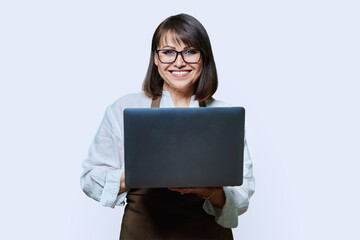 Portrait of middle aged woman in aapron with laptop on white background.