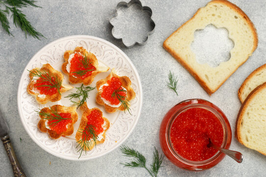 White bread canapes with ricotta or cream cheese, with salmon caviar and dill. A snack at a party. New Year, Christmas. Bread toast in the form of shells. Selective focus, top view and copy space