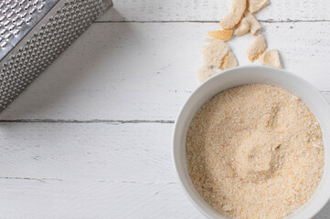 Fresh grated bread crumbs in a bowl on light background with copy space. Flat lay