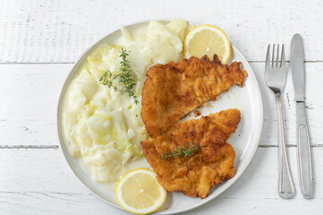 Schnitzel with cabbage vegetable and bechamel sauce on a plate on light wooden background. Flat lay