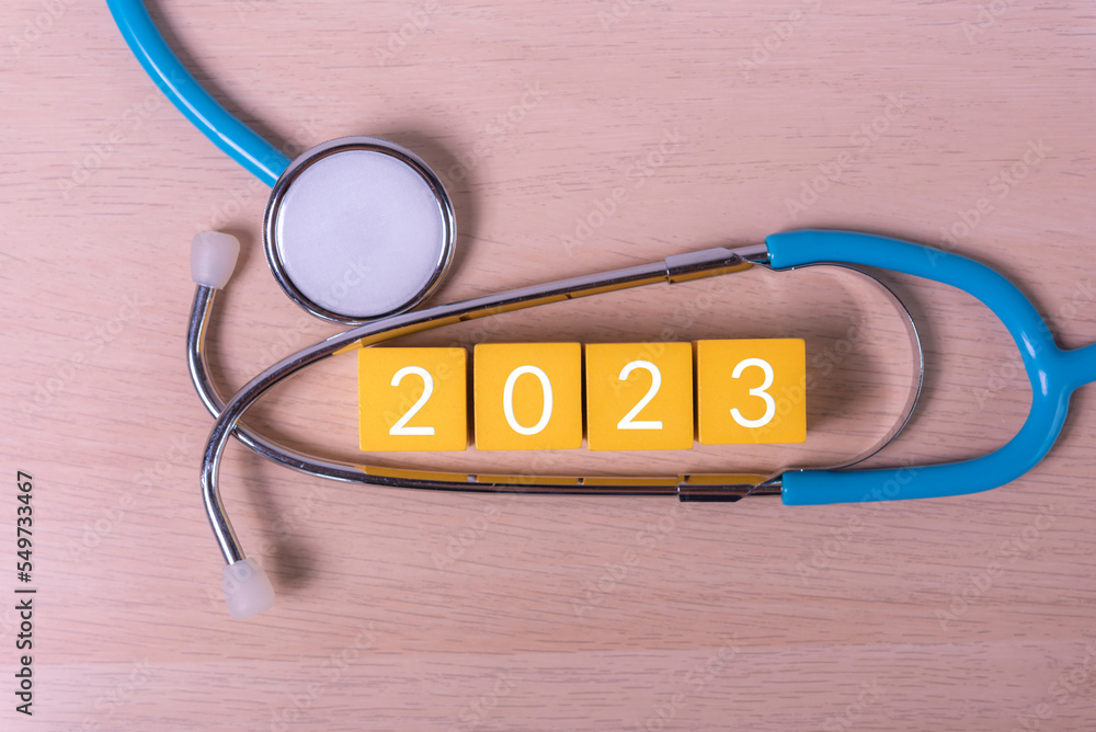 Aufkleber text 2023 year on wood cube building block and stethoscope , annual health check concept