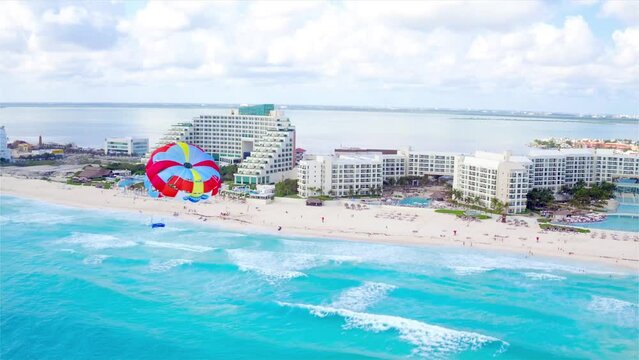 Parasailing aerial view. A couple paraskiing at tropical beach in bright day. 