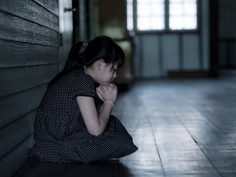 Sad Lonely Little Girl Thinking And Crying While Sitting On The Floor In Dark Room With An Attitude Of Sadness.Concept Of Depression Or Domestic Violence Child