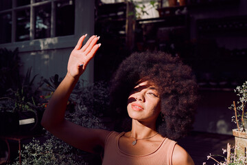 Sun, shadow and hand with a black woman covering her face from the light while standing outdoor....