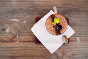 Obraz na płótnie Canvas Coffee shop, barista and hot chocolate art flowers decoration for relaxing and sweet drink break. Cafe, artisan and mocha foam with cocoa powder sprinkle in glass on wood table top view.