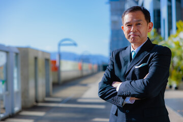 Middle-aged Asian man in black business suit at Kyoto station, Japan.