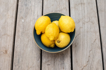 Citrons dans un saladier bleu posé sur un sol en lames en bois