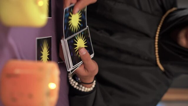 Pythoness man reads tarot cards on a table with candles, close up.