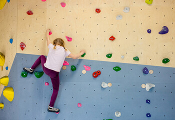 Girl child do bouldering known as free climbing exercise indoors leisure activity. © FotoHelin