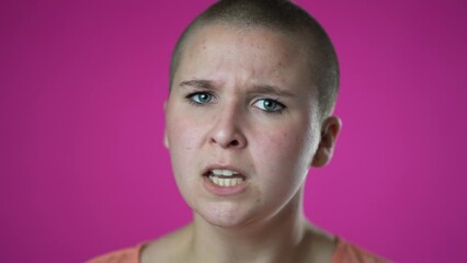 Portrait of angry frustrated despair upset portrait of gender fluid non binary young woman 20s closeup slow motion isolated on pink background