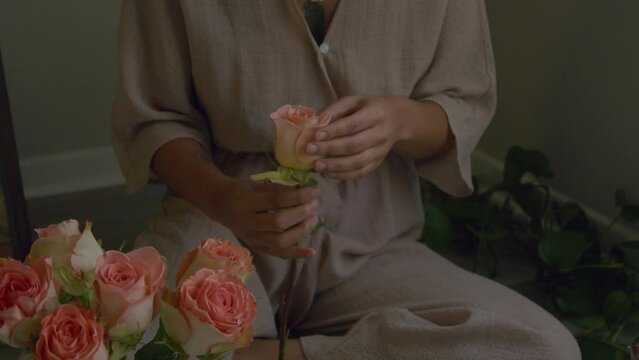 Young woman removing rose petals into bowl