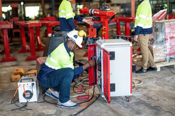 Electrician at robot factory measurement with multimeter testing current electric in control panel.
