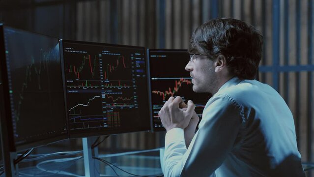 worried young investor sitting at a computer desk .