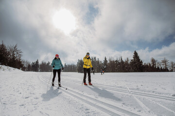 Senior couple skiing together in the middle of forest.