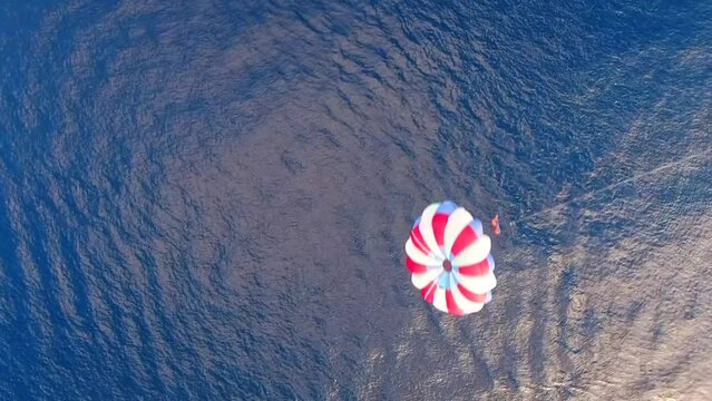 Parasailing aerial view. A couple paraskiing at tropical beach in bright day. 