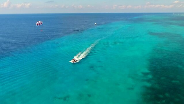 Parasailing aerial view. A couple paraskiing at tropical beach in bright day. 