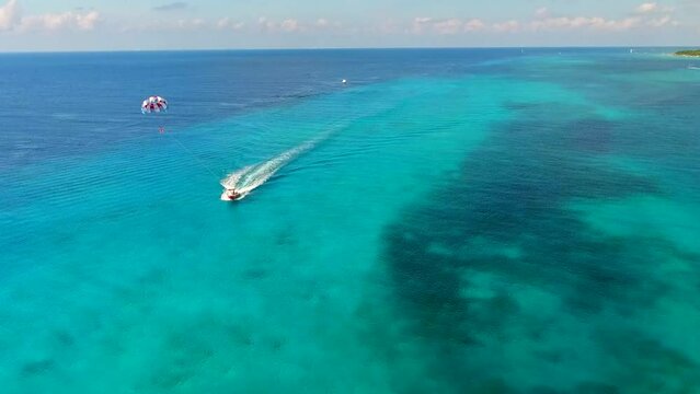 Parasailing aerial view. A couple paraskiing at tropical beach in bright day. 