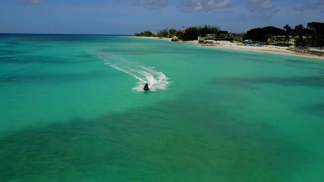 A couple rides on a jet ski, drawing a whimsical pattern in the water. Aerial view