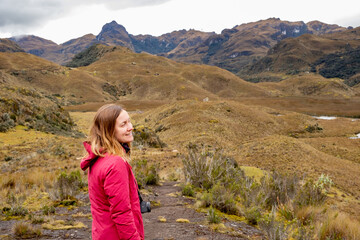 Naklejka na ściany i meble A smiley female hiker enjoying a spectacular view in the Cajas National Park in the highlands of Ecuador, tropical Andes.