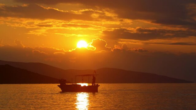 At sunset, the fisherman pulls the chain of his boat out of the sea. silhouette image.	