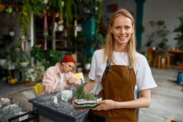 Portrait of young woman florist presenting beautiful floral composition
